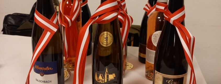 Das Bild zeigt Preise für die Gewinner der Honigprämierung. Zu sehen sind 6 Weinflaschen. Um jede Flasch ist eine Medaille gehängt.